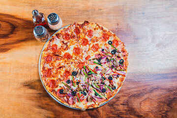 Top view of a supreme mixed pizza on wooden table. High angle view of mixed supreme pizza on wooden...