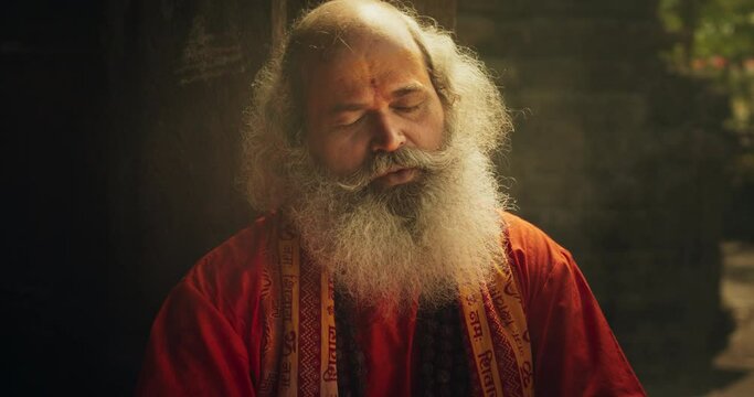 Slow Motion Close Up Portrait of Old Indian Monk Chanting in an Ancient Temple. Senior Guru Singing Religious Songs, Humble Male Devoted to Hinduism, Sharing Spiritual Wisdom and Love Through Worship