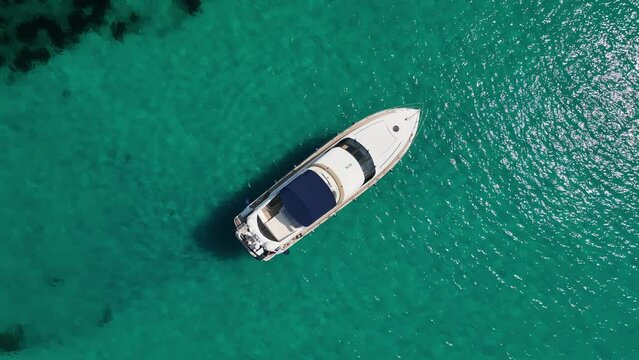 Top down drone shot of boat by anker on crystal clear water