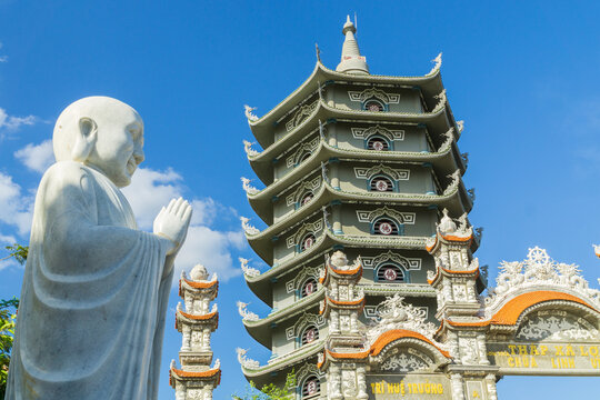 A marble statue of Buddha in front of an ancient Pagoda  temple against a blue sky at Da Nang in Vietnam