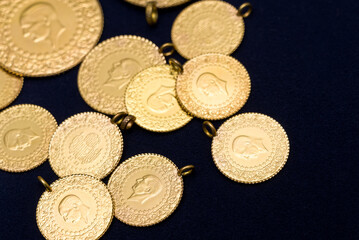 The pile of full, half and quarter Turkish gold coins on a dark navy blue background