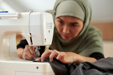Closeup image of muslim tailor sewing evening gown for client