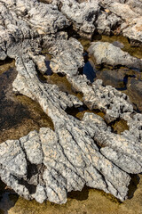 Travel close-up view, Gozo, Malta, stone wall background by the Mediterranean Sea, cliff pits and water