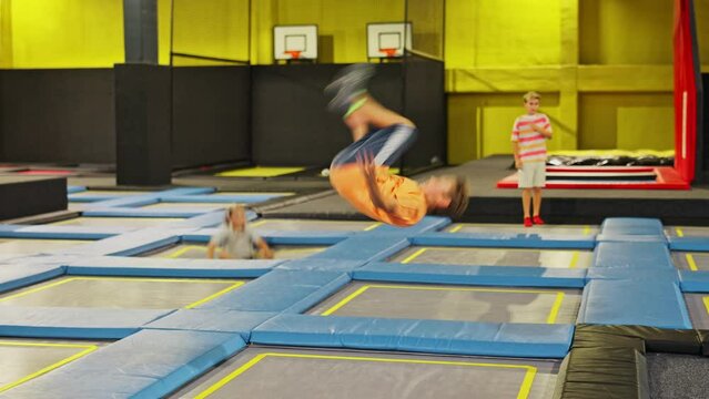 Happy active emotional preteen boy bouncing on trampoline while having fun in indoor amusement park