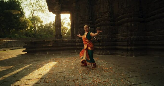 Slow Motion of an Indian Female Dancer Spinning and Performing a Traditional Dance in an Ancient Temple. Expressive Woman Wearing Beautiful South Asian Attire Dancing with Energy