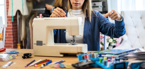 Portrait of young beautiful woman fashion designer stylish sitting and working with color samples.Attractive young girl working with colorful fabrics at fashion studio