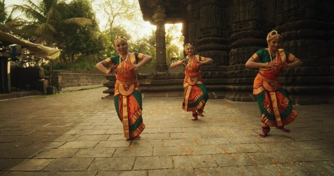 Slow Motion Portrait of Indian Women in Traditional Clothes Dancing Bharatanatyam in Colourful Sari. Three Expressive Young Females Performing Folk Dance Choreography in an Ancient Temple