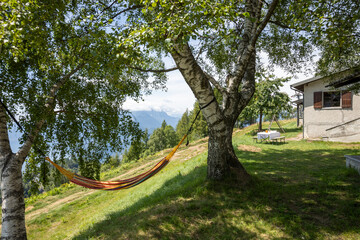 Hammock ready in a huge garden, in the background you can see the house and a table set.