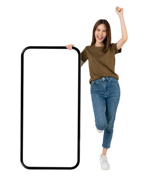 Beautiful Asian woman hand raised arms and fists clenched with big smartphone mockup of blank screen and smiling on grey background.