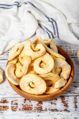 Dried apple slices in wooden bowl. Sun-dried natural apple slices on a white wood background