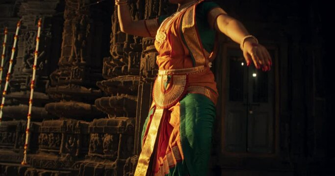 Energetic Indian Woman Showcases the Graceful Movement of Her Legs in Traditional Attire while Dancing Bharatanatyam. Female Dancer Enjoying the Spectacular South Asian Folk Dance in an Ancient Temple