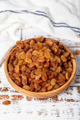 Raisins in wooden bowl. Sun-dried natural raisins on a white wood background