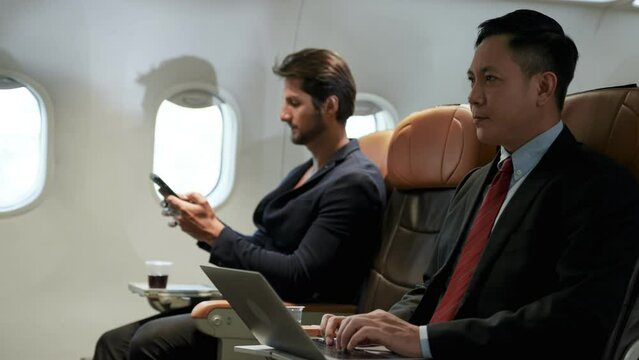 Businessman using laptop sitting on first class in plane during flight. Passenger business, Wealthy company executive travel working. Male working inside of an airplane.
