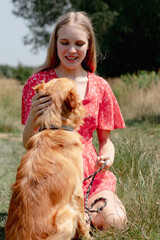 A young girl with long fair hair in a red jumpsuit hugs, strokes and plays with her dog.
- 632084289