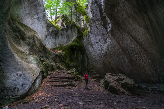 Frau in einer H&ouml;hle, die oben offen ist und durch den Spalt Licht hereinl&auml;sst, mit Pflanzen bewachsen. Das Kirchle bei Dornbirn ist ein m&auml;rchenhafter Platz, verborgen im Wald auf einem H&uuml;gel. Felsen