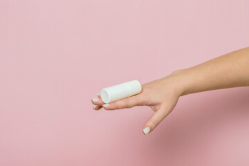 White bottle, drops for eye, nose or ear in hand on pink background. Pharmaceutical product.