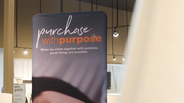 A 4K Panning Shot of A Retail Furniture Store Location Financing Promotional Banner Financing Credit Card Sign 'Purchase with Purpose' Orange and Blue Advertisement Background with Hanging Lights