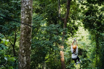 tourists wearing casual clothes on a zip line or awning experience in the Laos Asian rainforest.