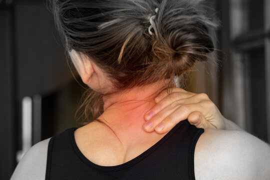 A young girl holds her hand on her neck from back pain at home, pain