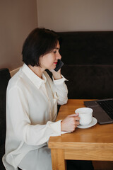 Image of happy woman using laptop while sitting at cafe