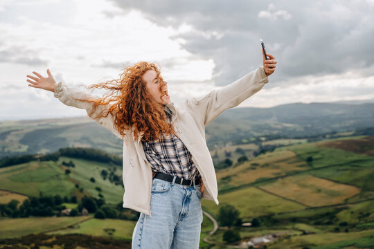 amazed Woman in jacket reaching the destination and taking selfie and shouting on the top of mountain at sunset. Travel Lifestyle concept The national park Peak District in England