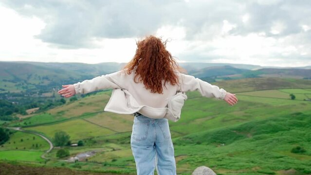 amazed Woman in jacket reaching the destination and taking selfie and shouting on the top of mountain at sunset. Travel Lifestyle concept The national park Peak District in England