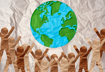 Cut-out paper people reaching for planet Earth, concept of planet and environment conservation.