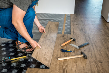 Worker laying vinyl floor, laminate or parquet covering at home renovation