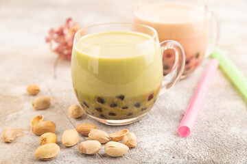Bubble tea with pistachio and caramel in glass on brown concrete, Side view, selective focus.
