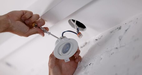 electrician installing recessed lamp in drywall ceiling. led lighting - Powered by Adobe