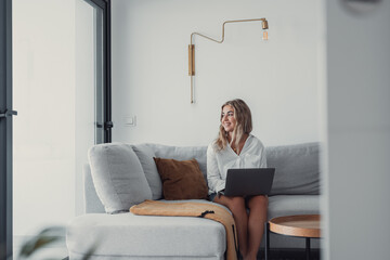 Portrait of one young attractive blonde woman using laptop pc computer on couch relaxing surfing...