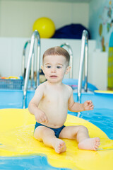 Development for babies. A little boy is learning to swim in the pool. Children's first swimming lessons. Development for babies
