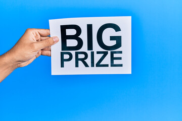 Hand of caucasian man holding paper with big prize message over isolated white background