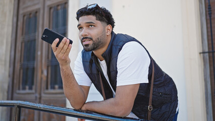 African american man sending voice message with smartphone at street