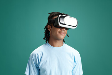 Portrait of young man wearing vr glasses against green studio background. Modern technologies and...