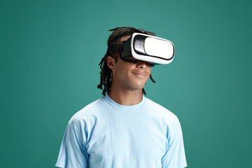 Portrait of young man wearing vr glasses against green studio background. Modern technologies and innovations. Concept of youth, human emotions, lifestyle, fashion, facial expressions, ad