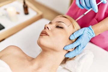 Fototapeta na wymiar Young caucasian woman lying on table having antiaging treatment at beauty salon