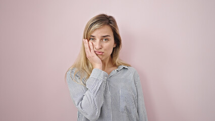 Young blonde woman standing with boring expression over isolated pink background