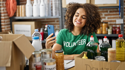 Young beautiful hispanic woman volunteer smiling confident having video call at charity center