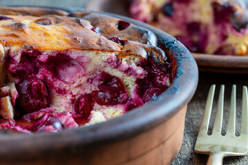 Sweet cottage cheese casserole with red cherry and semolina on wooden table. Ceramic bowl with...