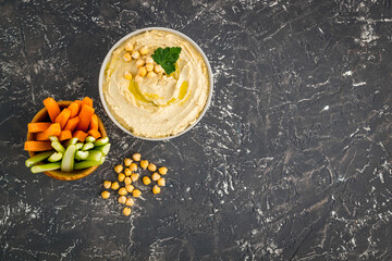 Obraz na płótnie Canvas Bowl of hummus with carrot sticks and chickpeas, top view
