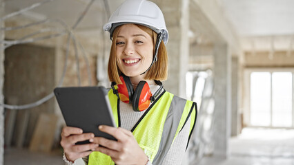 Young blonde woman architect smiling confident using touchpad at construction site