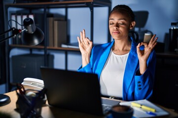 Beautiful african american woman working at the office at night relax and smiling with eyes closed doing meditation gesture with fingers. yoga concept.
