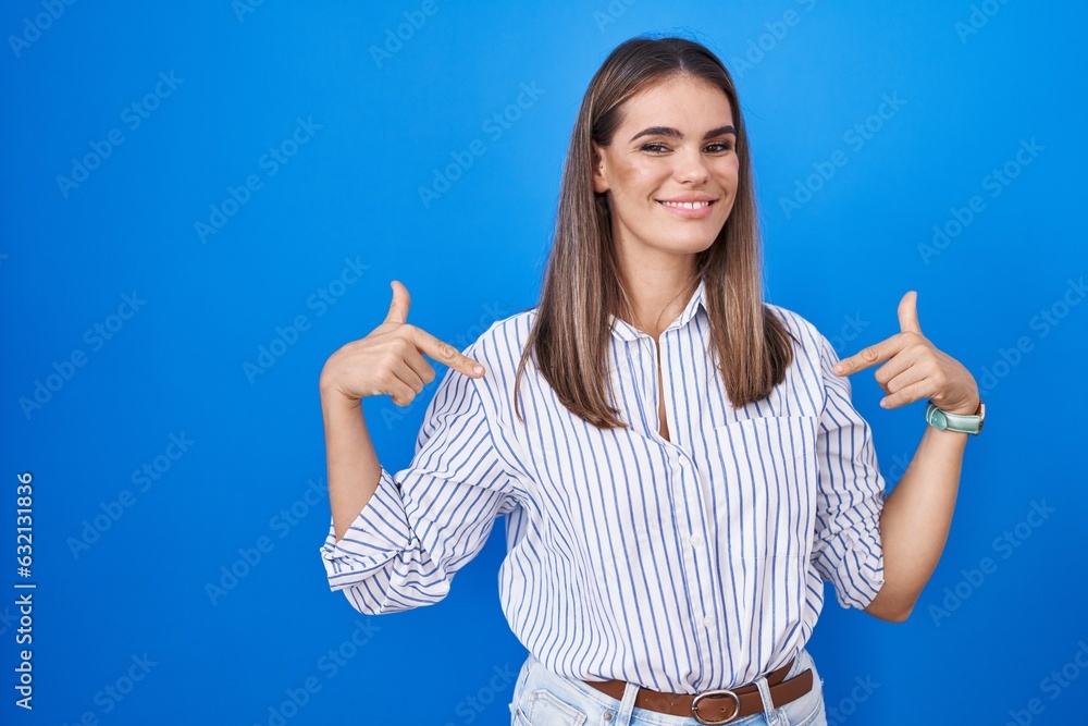 Sticker hispanic young woman standing over blue background looking confident with smile on face, pointing on