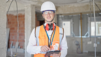 Young caucasian man architect smiling confident using touchpad at construction site