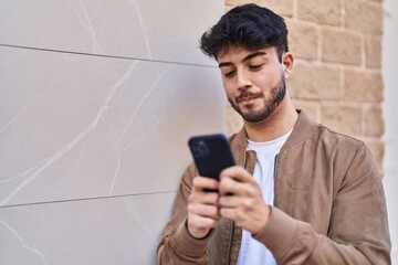 Young hispanic man using smartphone at street