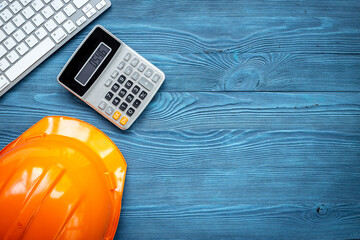 Calculator and construction helmet on architects desk, top view. Construction engineering