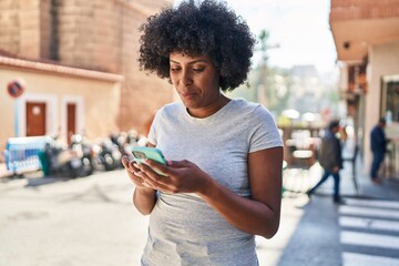 African american woman using smartphone with serious expression at street