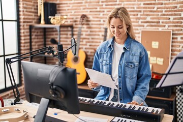 Fototapeta na wymiar Young blonde woman musician playing piano keyboard at music studio