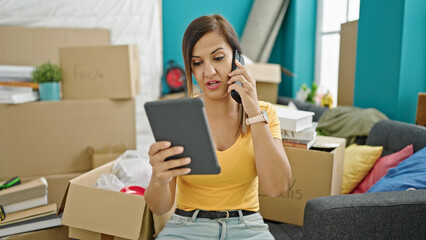 Middle eastern woman speaking on the phone using tablet at new home